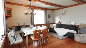 Um quarto aconchegante com uma mesa de jantar de madeira, cadeiras, um banco com almofadas, um sofá e uma cama.