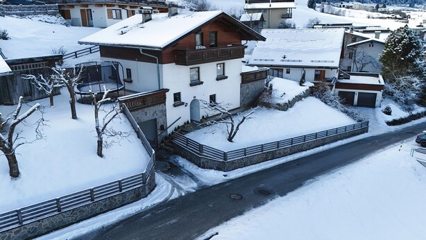 Bairro residencial com telhados cobertos de neve e uma rua pavimentada.