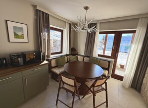 A dining area with a round table, chairs, a bench, a coffee machine, and a chandelier. - Alpenchalet Berggold - Holiday Home With Panoramic Views (Tulfes)