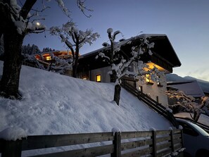 A snow-covered landscape with a building featuring a staircase and a car parked in front. - Alpenchalet Berggold - Holiday Home With Panoramic Views (Tulfes)