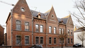 Un grand bâtiment en briques, doté de plusieurs toits à pignons et de nombreuses fenêtres.