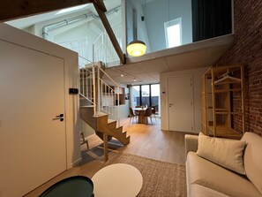 Un interior moderno con una escalera, un comedor y una zona de estar con un sofá.