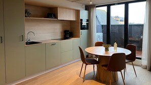Une cuisine moderne avec un coin repas, comprenant une table ronde et des chaises, un four encastré et une grande fenêtre offrant une vue dégagée.