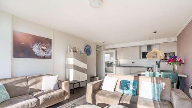 A modern living room with a sofa, coffee table, and a painting of a dandelion on the wall. - 4-person Apartment With Island View (De Koog)
