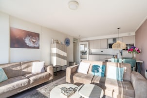 A modern living room with a sofa, coffee table, and a painting of a dandelion on the wall.