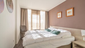 A neatly made bed with white bedding and a wooden headboard, a chair, and two framed pictures on the wall. - 4-person Apartment With Island View (De Koog)