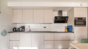 A modern kitchen with white cabinets, a black range hood, and built-in appliances. - 4-person Apartment With Island View (De Koog)