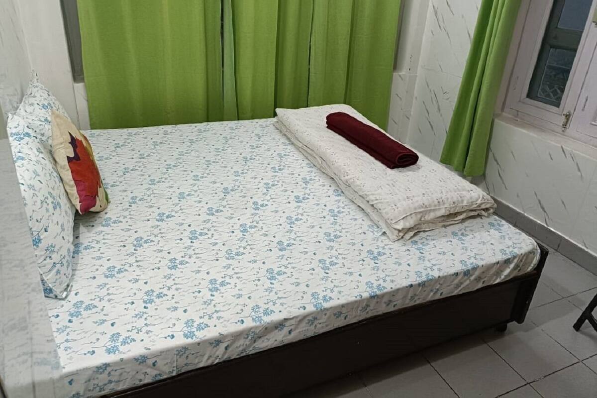 Un letto con una coperta a fiori, un cuscino rosso e una coperta bianca.