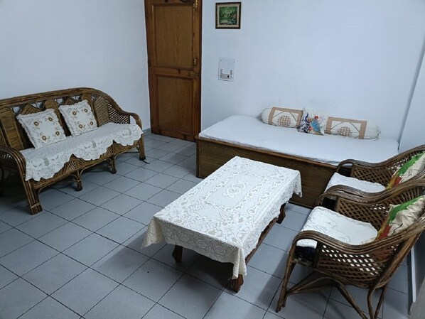 Une pièce comprenant un canapé en bois, un banc assorti et une petite table recouverte d’une nappe en dentelle.