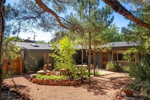 A house with a stone patio, a small garden with a tree, and a wooden fence. - Modern Fully Remodeled 3 Bedroom Gem with a Hot Tub and Close to Everything (Sedona)