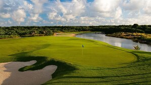 Ein Golfplatz mit Fahne, Bunker und einem Wassengraben.