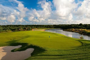 Ein Golfplatz mit Fahne, Bunker und einem Wassengraben.