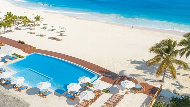 Ein Resort mit Swimmingpool, Strand und Palmen.