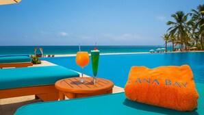 Blick auf das Schwimmbecken mit Liegestühlen, einem Tisch mit Getränken und einem Handtuch mit dem Aufdruck "CANA BAY".