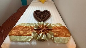Un lit simple avec un oreiller en forme de cœur et un nœud décoratif sur la couvre-lit.