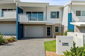 A two-story residential building with a garage, a balcony, and a mailbox. - Sandy Toes - Walk to Beach, Pet Friendly, Stylish (Woolgoolga)
