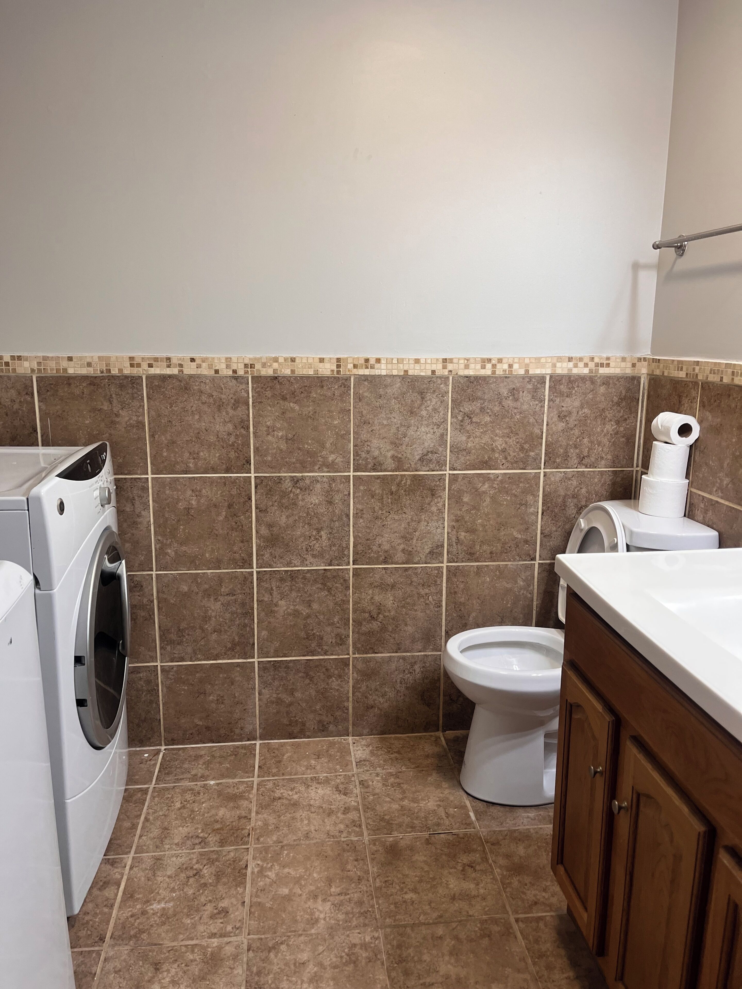Een badkamer met een wasmachine, toilet en wastafel.