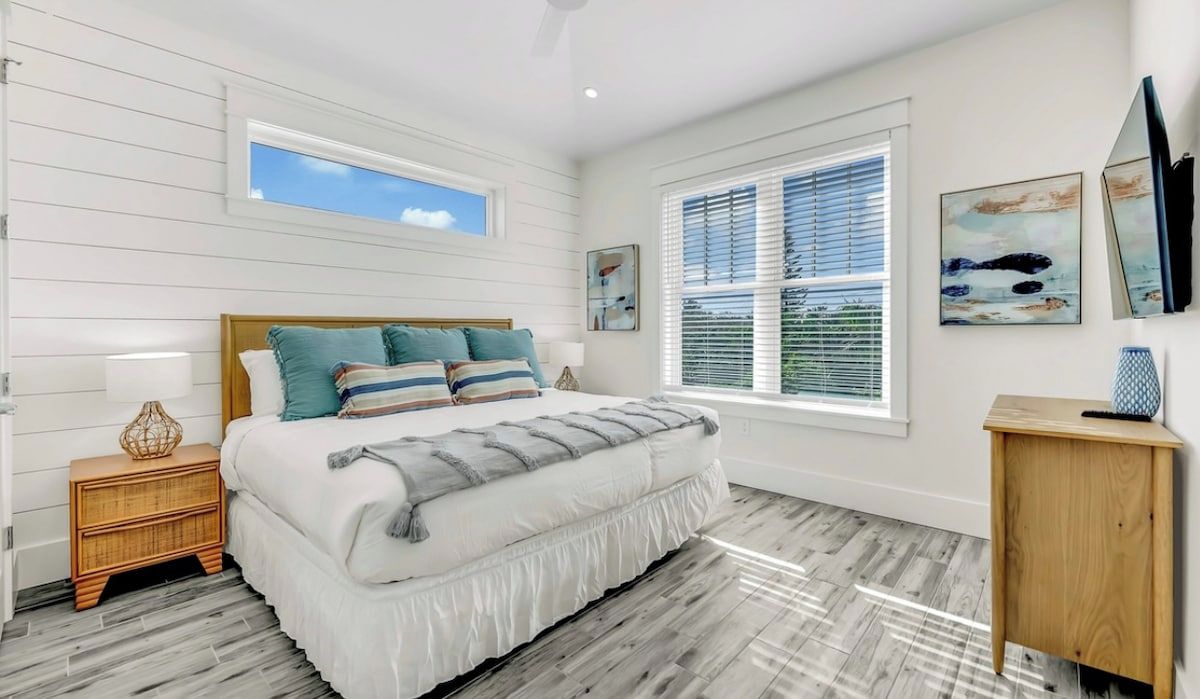 A bedroom with a bed, a nightstand, a window, and wall art.