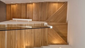 Un interior moderno con una escalera de cristal que lleva a una plataforma de madera.