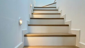Una escalera con escalones de madera y paredes blancas.