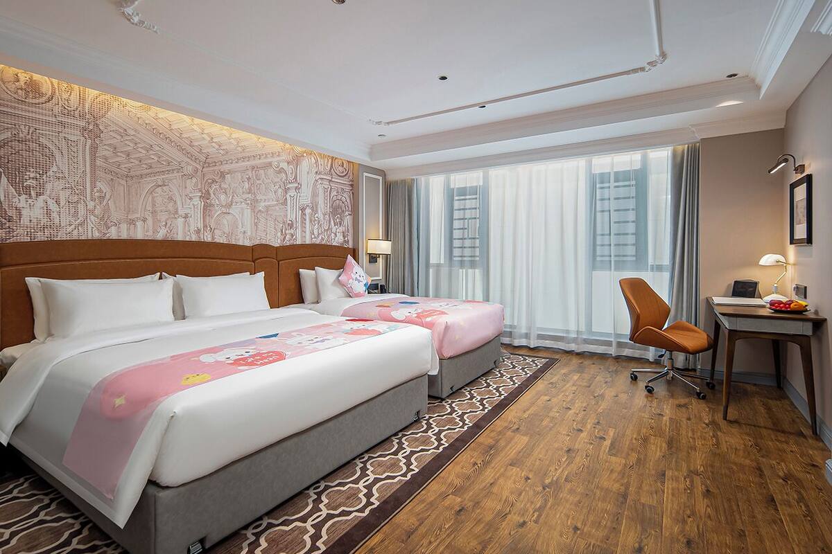 Une chambre d’hôtel avec deux lits, un bureau et une chaise.
