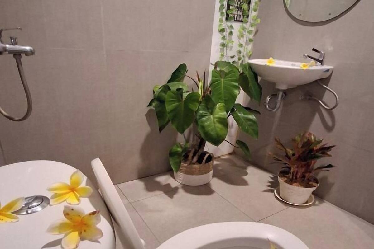 A bathroom with a toilet, a sink, and two potted plants.