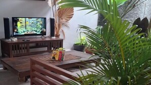 A cozy living room with a wooden coffee table, a television, and various potted plants. - Bring in House Yogyakarta (Mantrijeron)