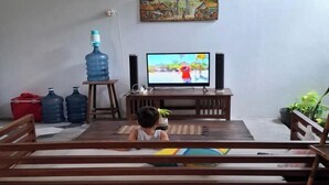 A living room with a television, wooden furniture, and a painting on the wall. - Bring in House Yogyakarta (Mantrijeron)