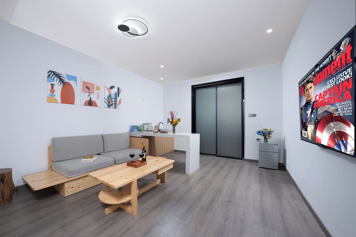 Ein modernes Wohnzimmer mit grauem Sofa, Couchtisch aus Holz und Kunstwerken an den Wänden.
