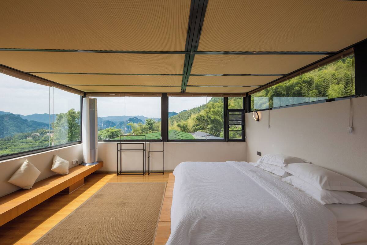 Ein Schlafzimmer mit einem großen Bett, einer Bank und Blick auf die Berge.