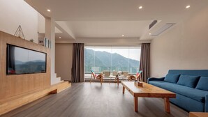 Een moderne woonkamer met een grote televisie, een blauwe bank en een houten salontafel.