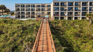 Un puente de madera que conduce a un edificio moderno de varios pisos con balcones.