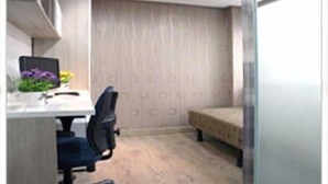 Un petit bureau avec un bureau, une chaise et un lit.