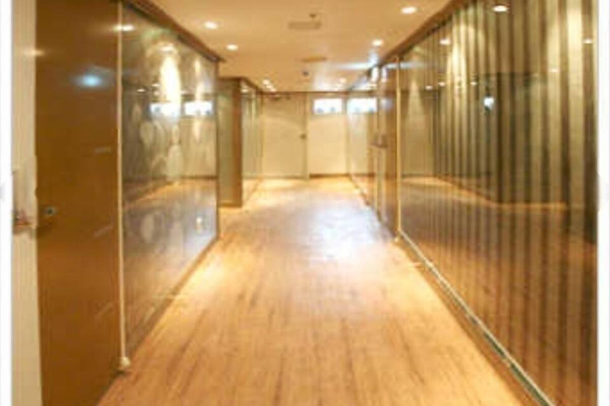 A hallway with wooden flooring and glass walls, leading to a door at the end.