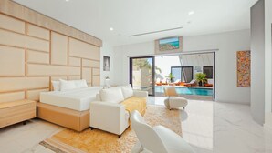 A modern bedroom with a large bed, a sofa, and a view of a swimming pool. - NEW LUX 5 Bed 5 Bath Pool Near To Beach By Bocobay (Noord)