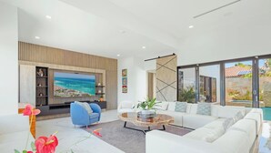 A modern living room with a large TV, white sofas, a blue armchair, and a coffee table. - NEW LUX 5 Bed 5 Bath Pool Near To Beach By Bocobay (Noord)
