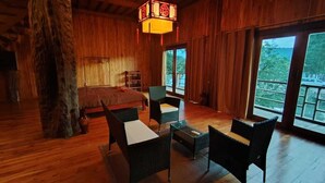 A wooden interior with a bed, wicker furniture, and a hanging light fixture. - Nirvana Archipel Resort (Vang Vieng)