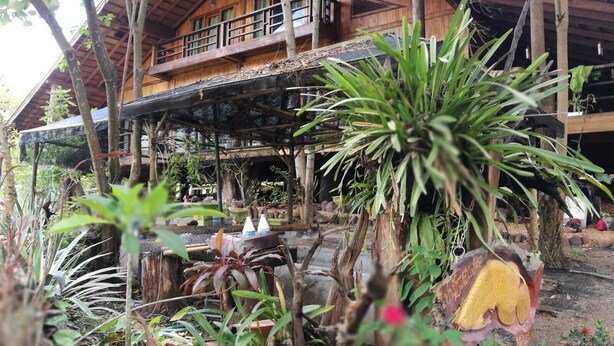 A wooden building with a balcony, surrounded by tropical vegetation. - Nirvana Archipel Resort (Vang Vieng)