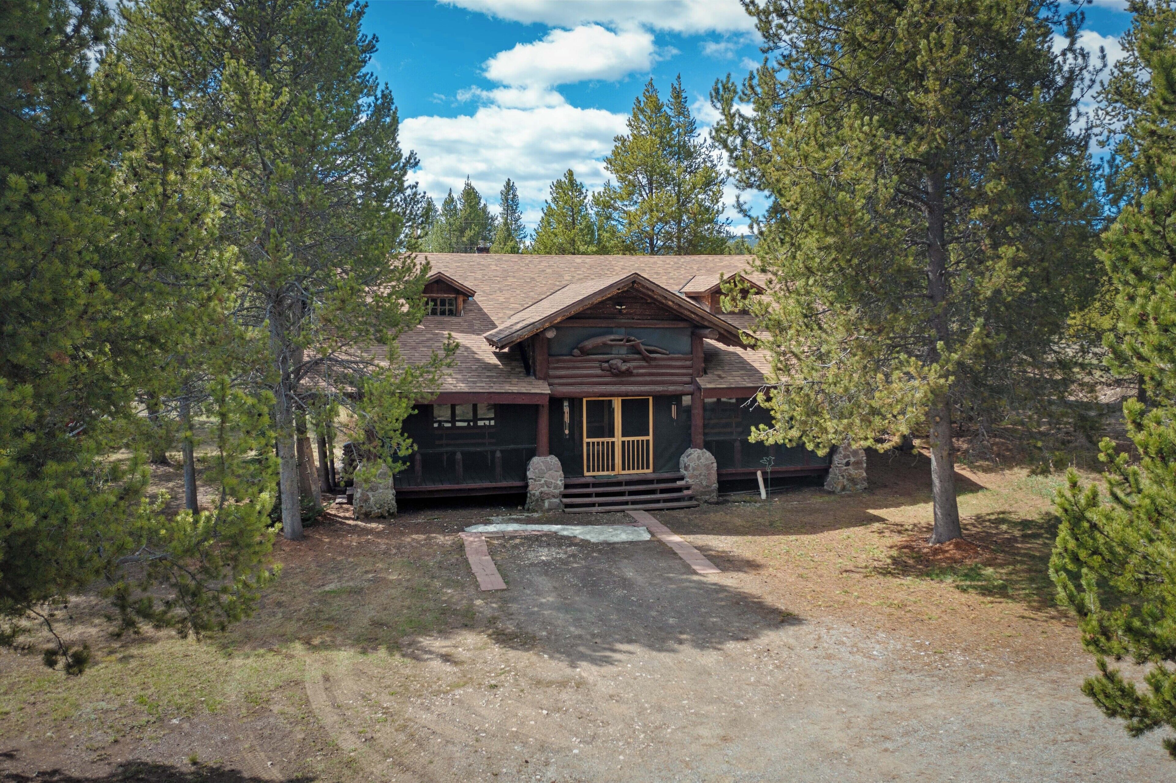 A lodge with a large front porch, a stone entrance, and a mountain backdrop.