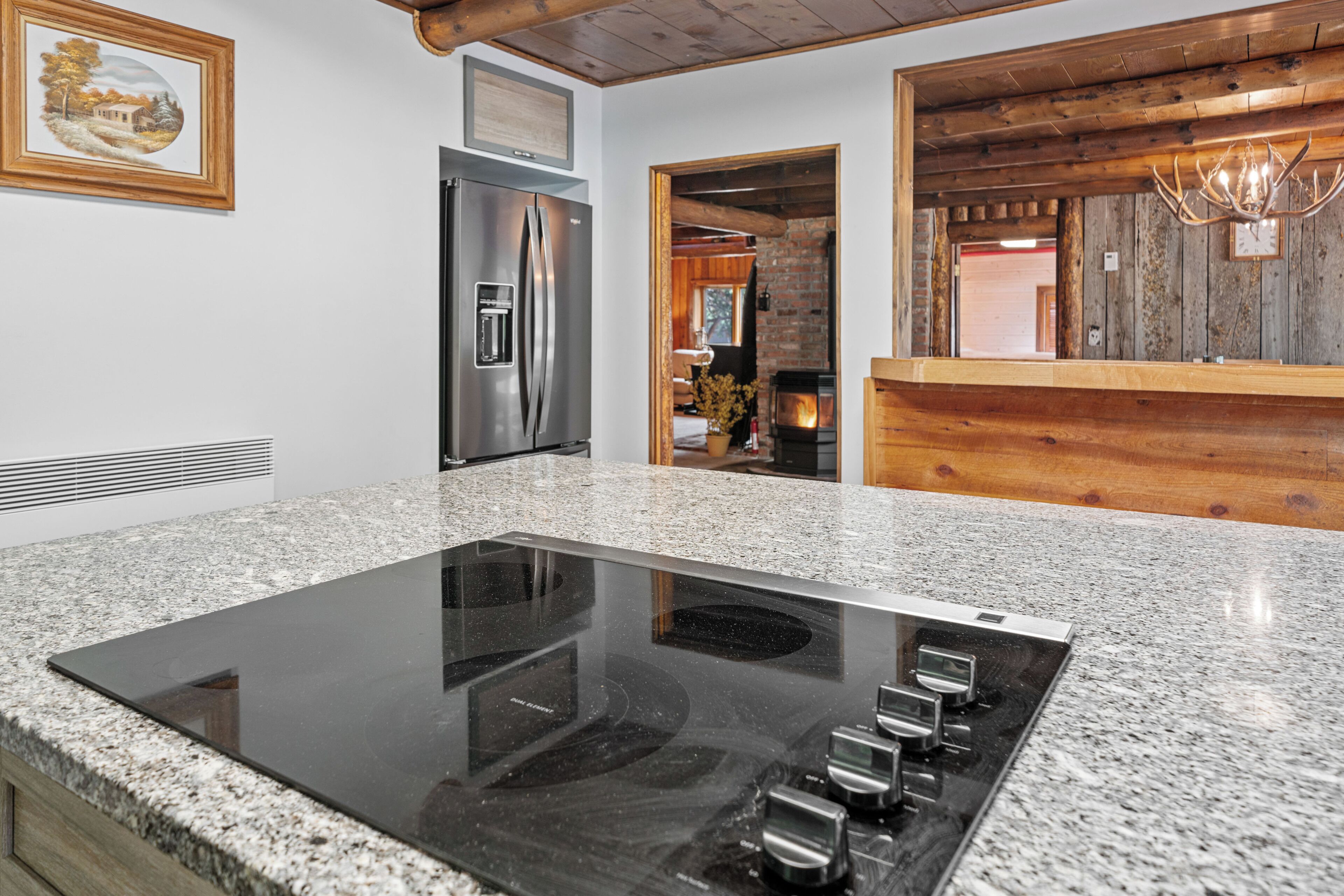 A kitchen with a granite countertop, stainless steel appliances, and a wooden interior.