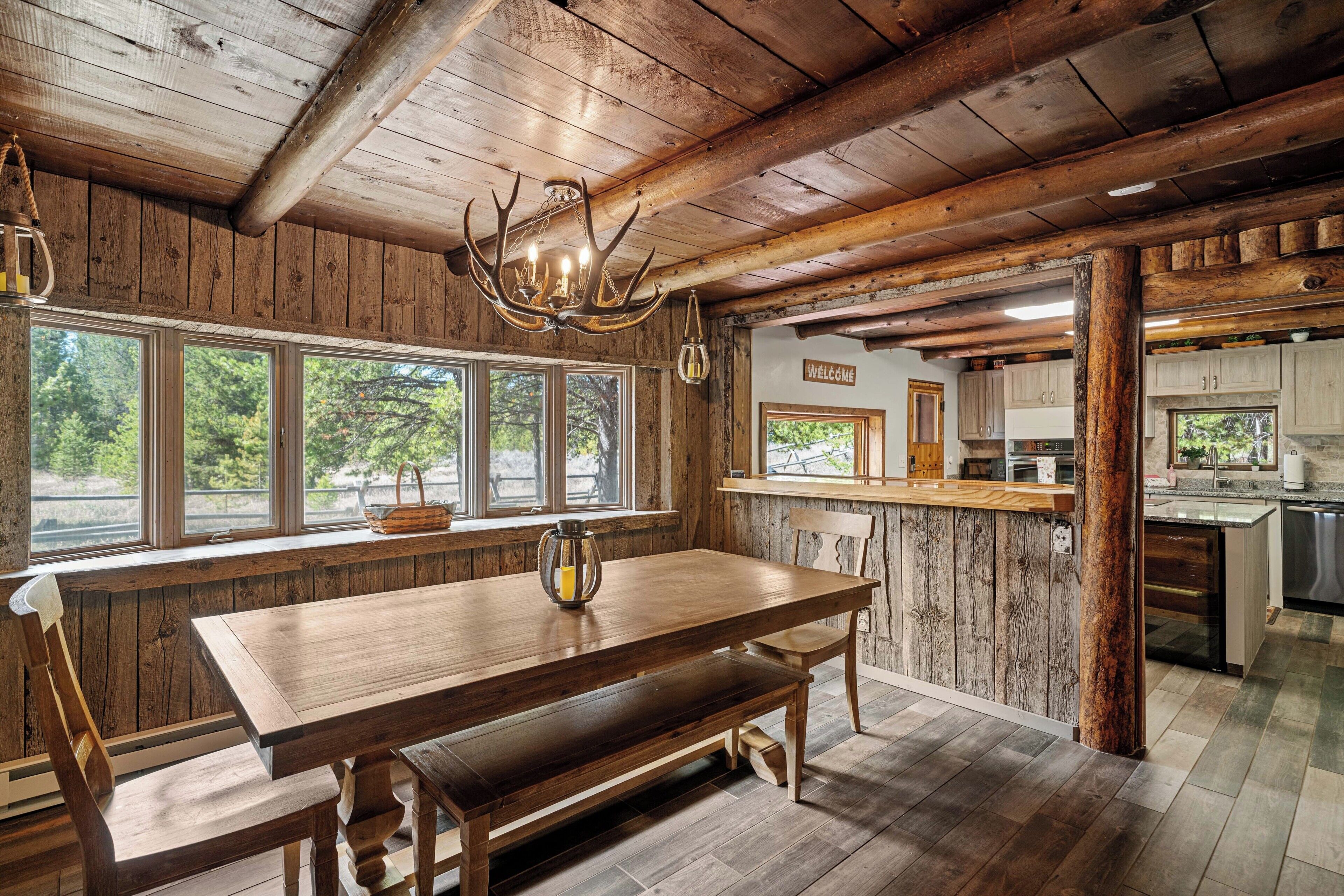 A rustic wooden interior with a large dining table, wooden beams, and a chandelier.