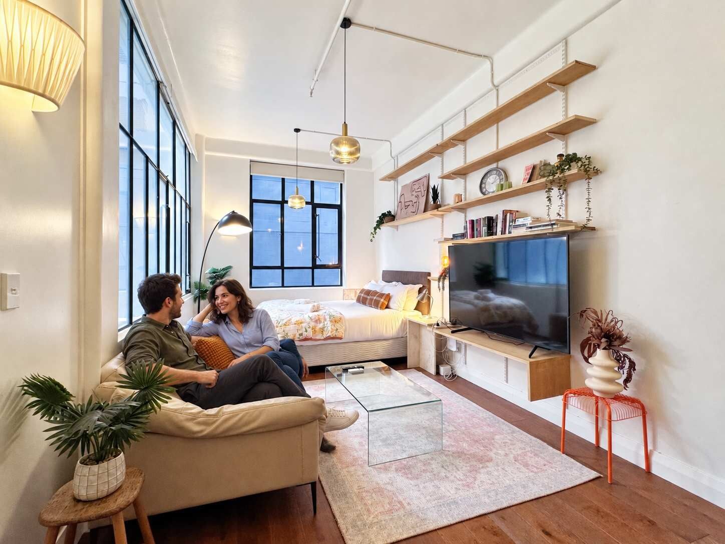 A modern living room with a sofa, a coffee table, a TV, and a bookshelf.