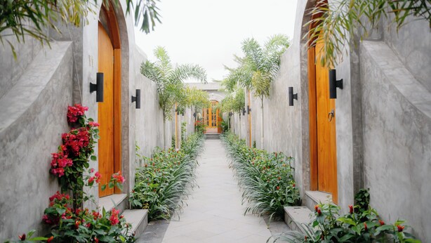 Un pasillo con puertas arqueadas, suelo de baldosas y plantas en macetas.