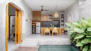 Una cocina moderna con armarios de madera, un comedor con sillas y una piscina pequeña.