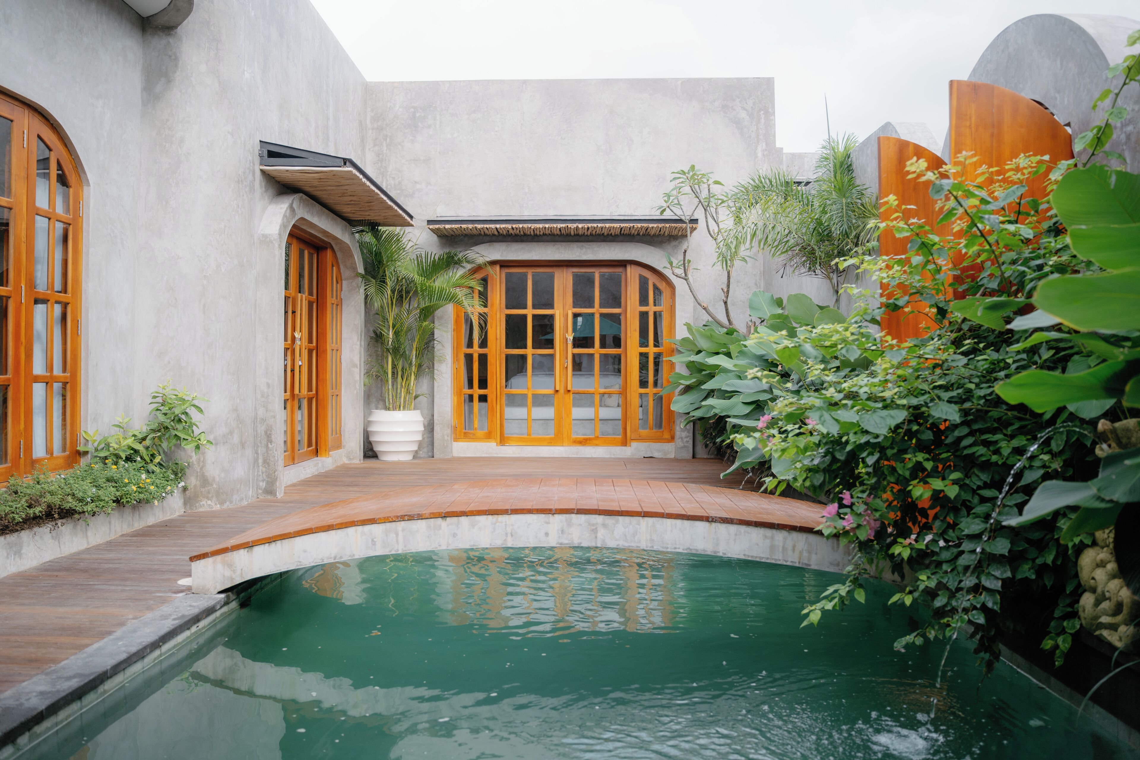Ein Innenhof mit Pool, Holztüren und einem Betongebäude.