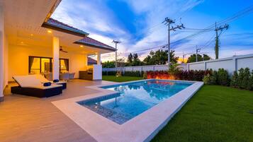 Un área de piscina exterior moderna con una tumbona y una zona de barbacoa.