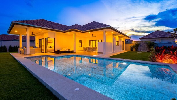 Una moderna casa con piscina, patio coperto e prato curato.