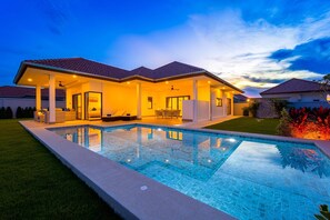 A modern house with a swimming pool, covered patio, and a well-maintained lawn. - New Modern 3 Bedroom Villa MB35 (Hua Hin)