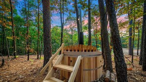 Un jacuzzi en un bosque, con una escalera de madera que lleva hasta él.