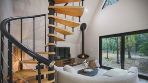A modern interior with a spiral staircase, a cozy seating area, and a fireplace. - Secluded A Frame Retreat,hot tub,sauna (Wright City)